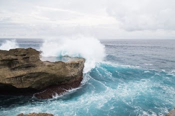 brown cliff with seawave during daytime