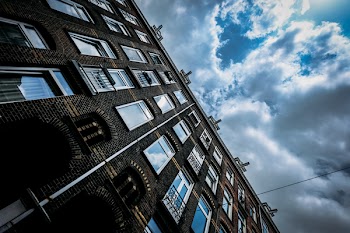 Brown Concrete Building Under Blue and White Cloudy Sky
