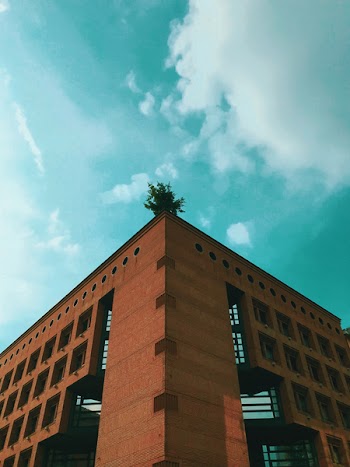 Brown Concrete Building Under Teal and White Cloudy Sky at Daytime