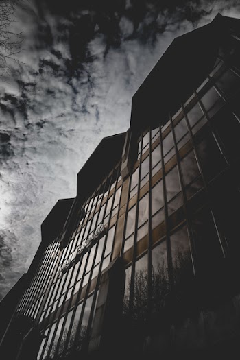 Brown Concrete Building With Glass Window Under Gray Sky