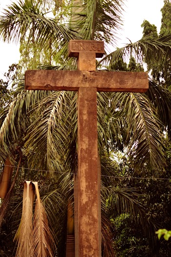Brown Concrete Cross Near a Palm Tree