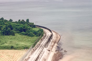 Brown Concrete Road Near Body of Water