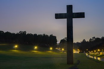 Brown Cross Statue on Green Grass Field With Turned on Light during Nighttime