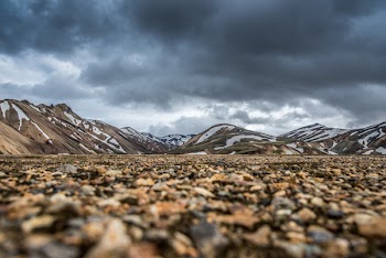 Brown Field Near Mountain Under Cloudy Sky