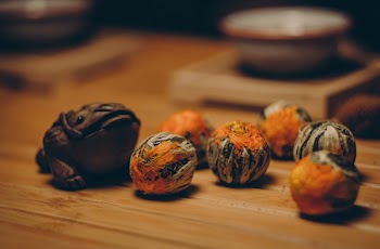 Brown Frog Figurine Beside Orange and Gray Fruits