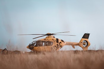 brown helicopter landing on brown grass field during daytime