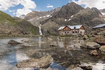 brown house near at body of water and surrounded by rocks during daytime