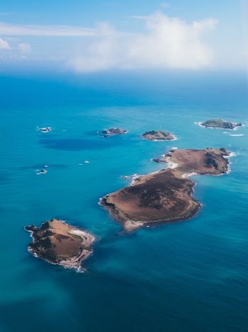 brown island on body of water under cloudy sky
