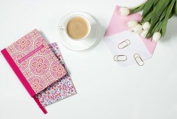 Brown Latte in Ceramic Mug Near Pink and White Floral Textile and White Tulips