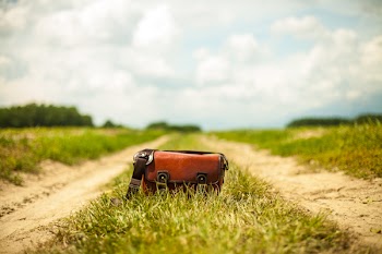 Brown Leather Baguette Bag on Green Grass Field With Vehicle Track