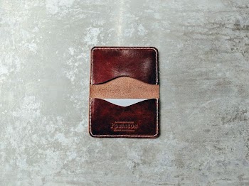 brown leather card organizer on gray pavement