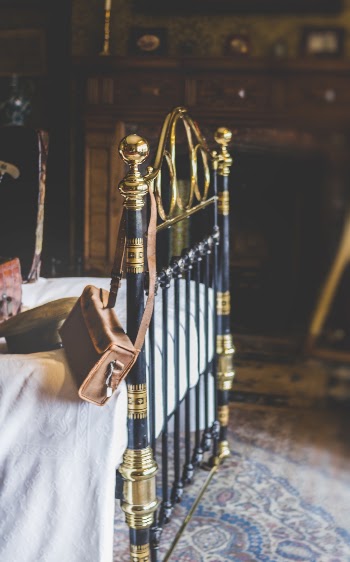 Brown Leather Crossbody Bag On Black And Gold Bed Frame