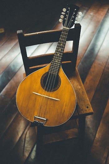 Brown Mandolin String Instrument on Brown Wooden Chiar