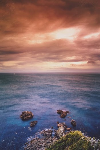 Brown Mountain Near Sea Under Cloudy Sky during Golden Hour