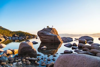 brown rock formation beside calm body of water near mountain at daytime