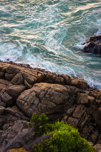 Brown Rock Formation Beside Green Body of Water at Daytime