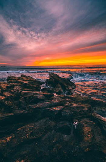 Brown Rocks Beside Body of Water during Dusk
