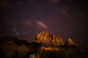 brown rocky mountain near body of water at night