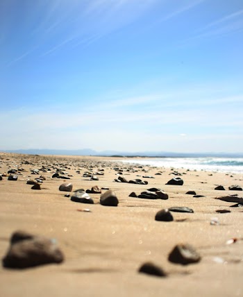 Brown Sand Seashore With Brown Pebbles Under White and Blue Cloudy Skies