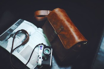 brown sling bag beside SLR camera on black surface