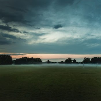 brown soccer field under cloudy sky