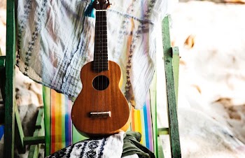 brown ukulele near beige textile