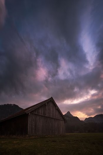 brown wooden barn under gray clouds