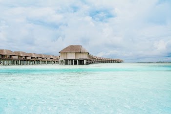 brown wooden houses over body of water under cloudy sky during daytime