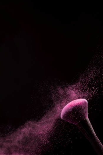 Brush for makeup with powder dust on dark background Free Photo