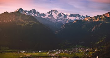 Buildings on Grass Field Near Mountains