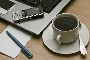 business communications - laptop, cell mobile phone  and cup of coffee on a desktop