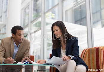 Business people discussing paperwork in office lobby