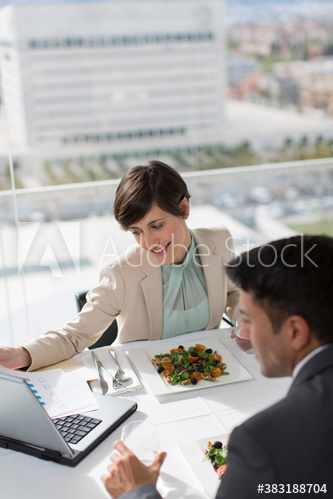 Business people eating lunch and working at laptop in conference room