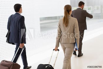 Business people pulling suitcases in office corridor
