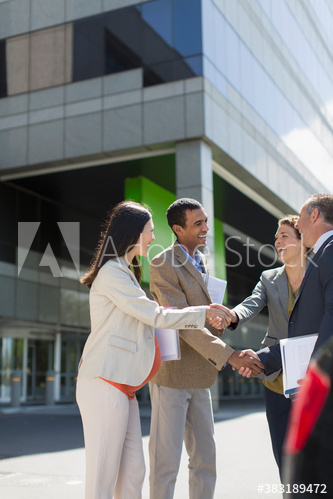 Business people shaking hands in sunny parking lot