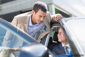 Business people talking at car door