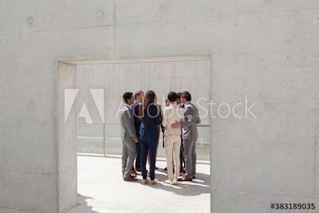 Business people talking in circle in sunny patio doorway