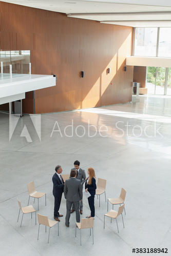 Business people talking in circle of chairs in modern lobby