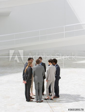 Business people talking in circle on sunny patio