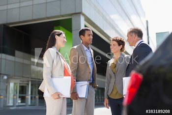Business people talking in sunny parking lot