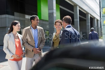 Business people talking in sunny parking lot