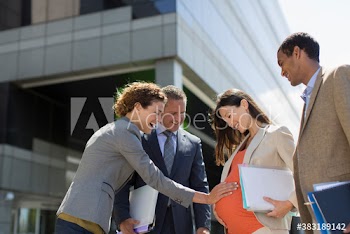 Business people touching stomach of pregnant colleague