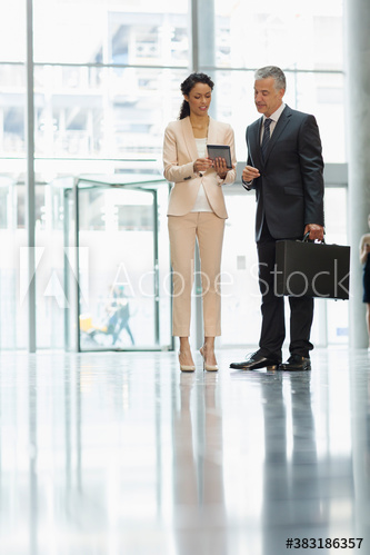 Business people using digital tablet in office lobby