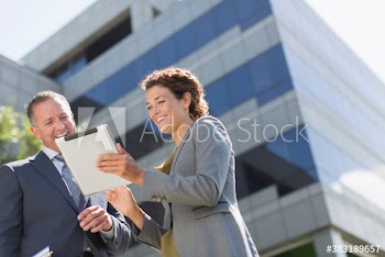 Business people using digital tablet outside office building