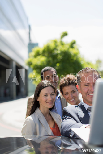 Business people using laptop on car in parking lot