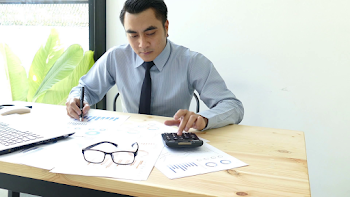 Businessman analyzing investment charts with calculator laptop ...