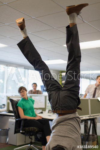 Businessman doing handstand in office