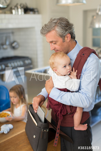 Businessman father preparing for work with baby son in carrier