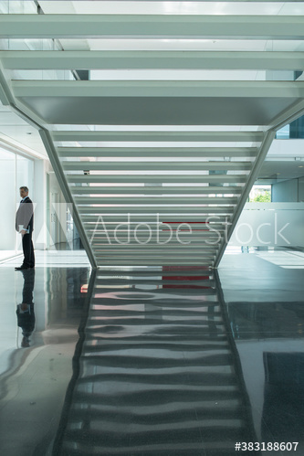Businessman in modern lobby with staircase