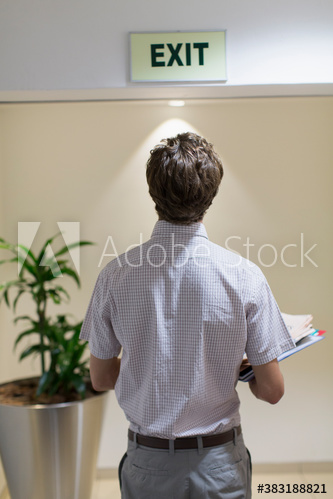 Businessman looking up at exit sign